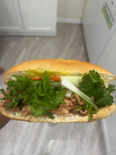 A golden bánh mì with savoury filling, cucumber, carrot, and cilantro